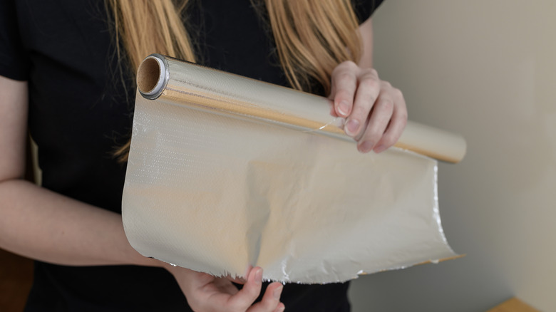 Woman unrolling aluminum foil