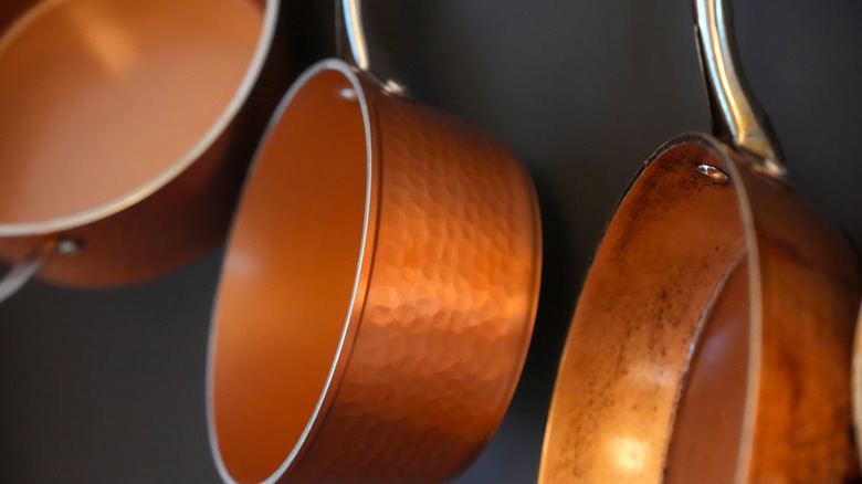 Shining copper pots and pans hanging on wall