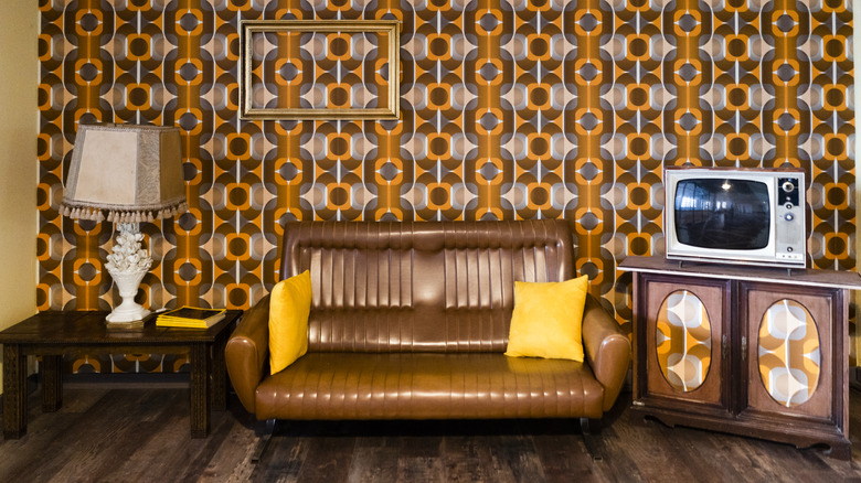 Retro living room with orange and brown wallpaper, wood furniture and brown couch