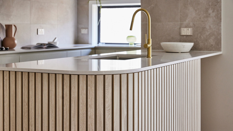 Fluted wood kitchen island with brass faucet
