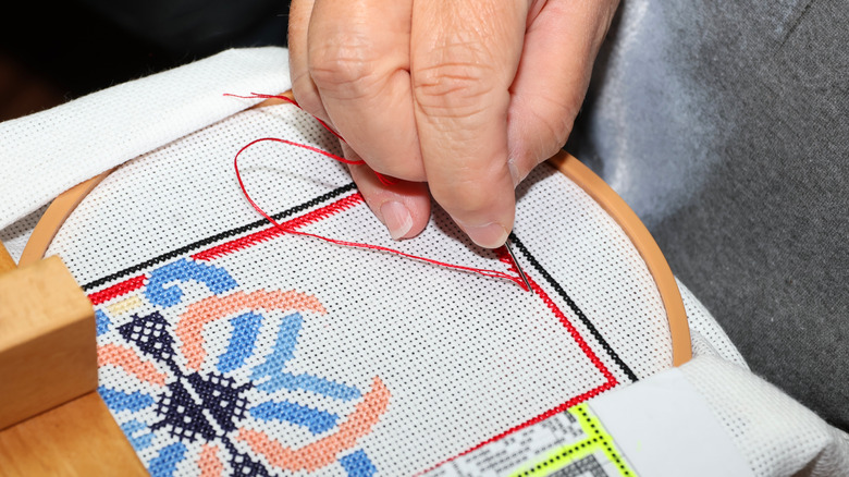 Closeup of a hand working on needlepoint