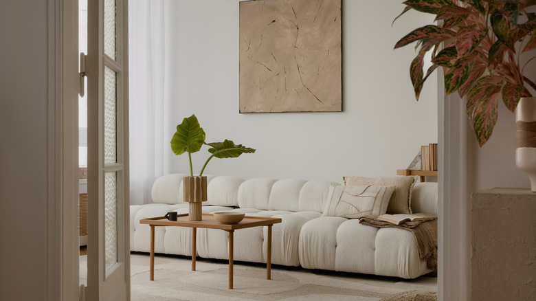 A space with a couch and a coffee table in a home, set behind an open frosted glass door.