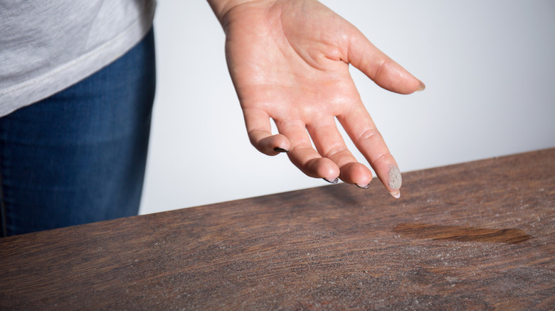 A finger is dusty after touching a surface coated in dust