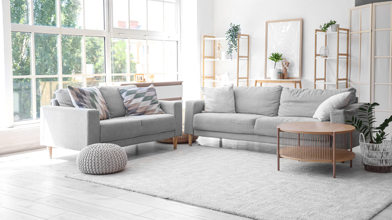 Living room with muted tones of gray and natural woods featuring a couch and love seat with pillows