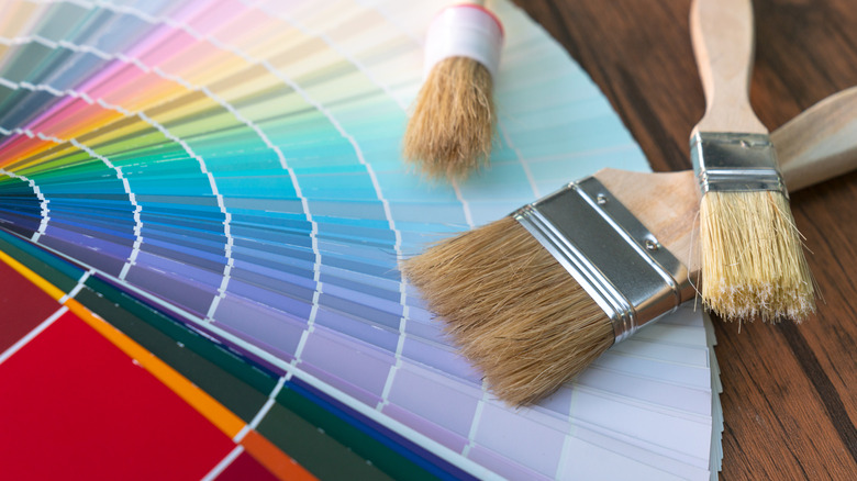 A series of color samples from all shades and three paint brushes on a wooden table