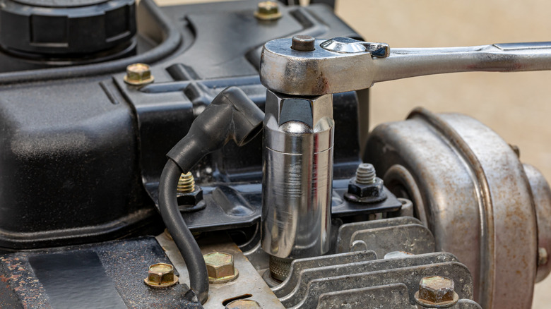 Removing a mower spark plug with its wire cap already disconnected