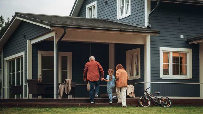 Family walking up to a front porch with chairs and a bike leaning against the house