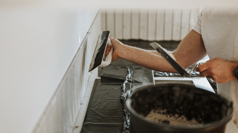 Man putting up tile in a kitchen under renovation