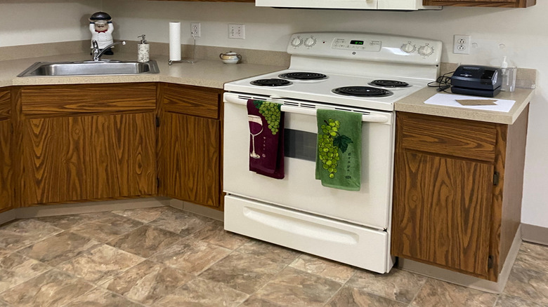 Outdated kitchen with dark wooden cabinets and white appliances