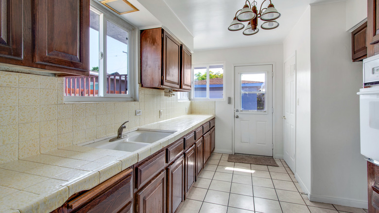 Outdated kitchen with dark cabinets and tile countertops