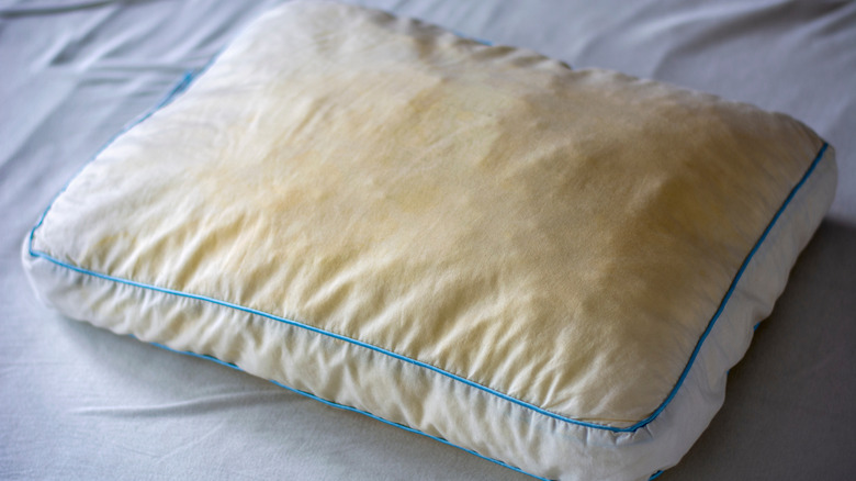Dirty yellowed pillow on a bed sheet