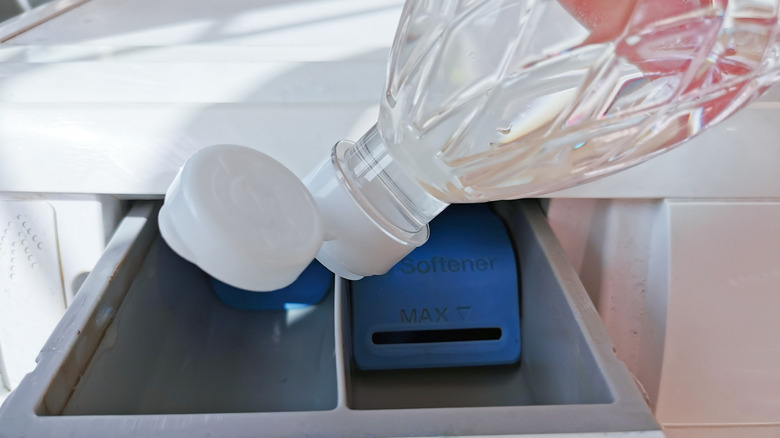 Pouring a bottle of vinegar in the washing machine dispenser drawer