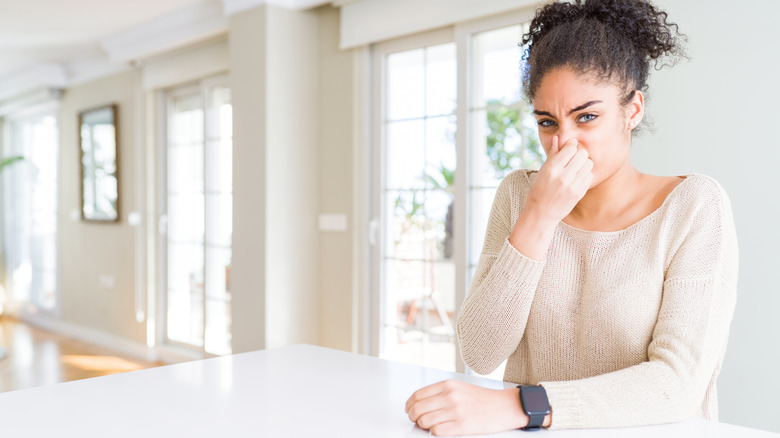 Woman holding nose smelly home