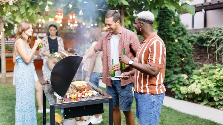 Smiling people grilling food outdoors