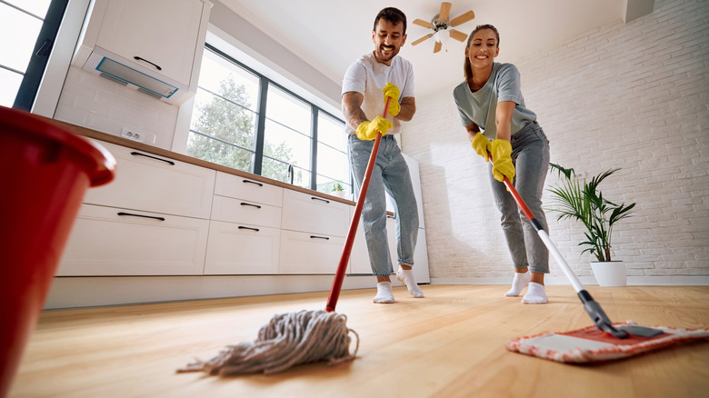 low angle view of smiling couple mopping wooden floor