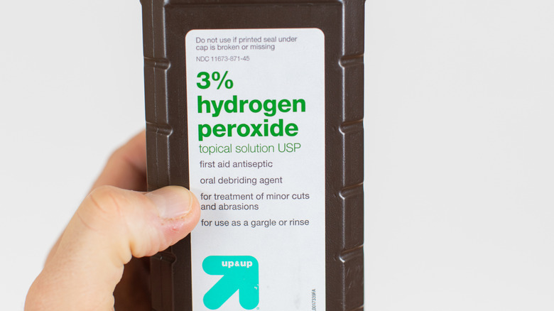 Hand holding a bottle of hydrogen peroxide 3%