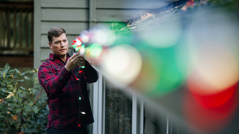 A man putting up Christmas lights on his patio