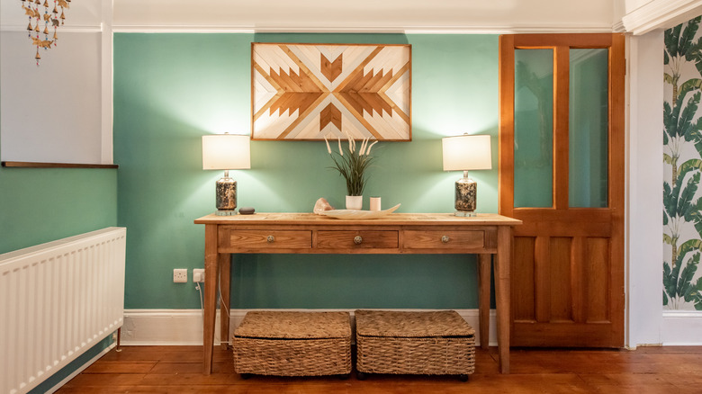 A rustic-inspired entryway with wood table, art, and which baskets.