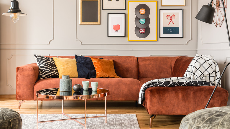 Eclectic living room interior with comfortable vintage velvet corner sofa and pillows.