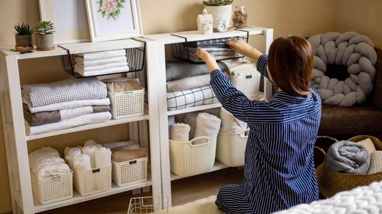 person tidying up linen storage