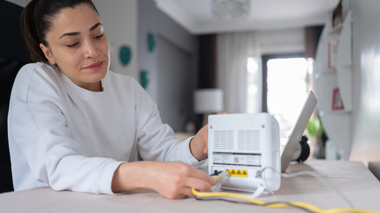 Person plugging in Wi-Fi router