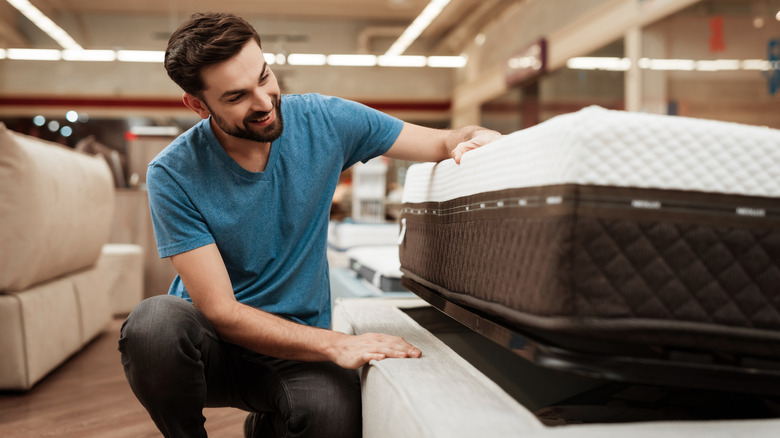 Man smiling and looking at a mattress in the furniture store