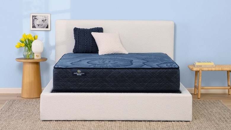 The Serta mattress with no cover on a box frame in a staged room
