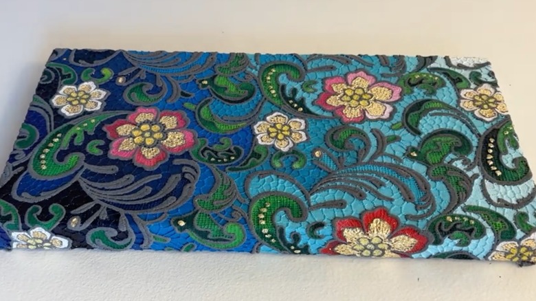 A canvas covered with flower-designs on lace and painted over.