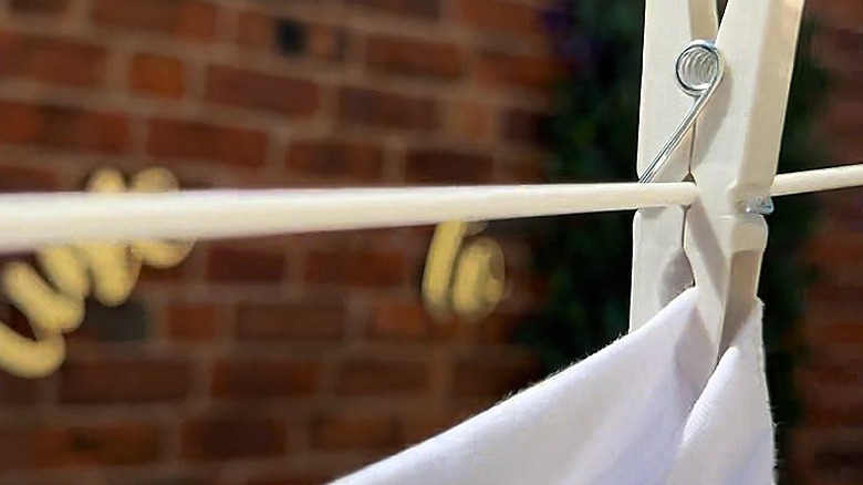 Close-up of a clothespin pinned to a clothesline by the small hole by the spring