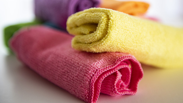 A stack of multi-colored, rolled-up microfiber cloths with red and yellow cloths closest to the camera