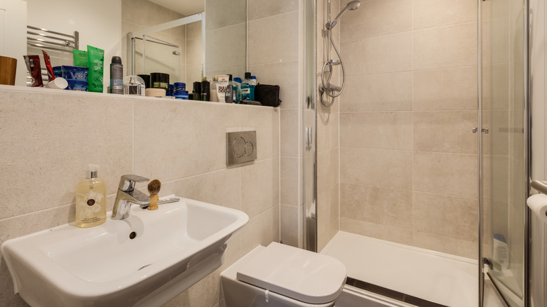 A small bathroom with a shelf cluttered with toiletries.