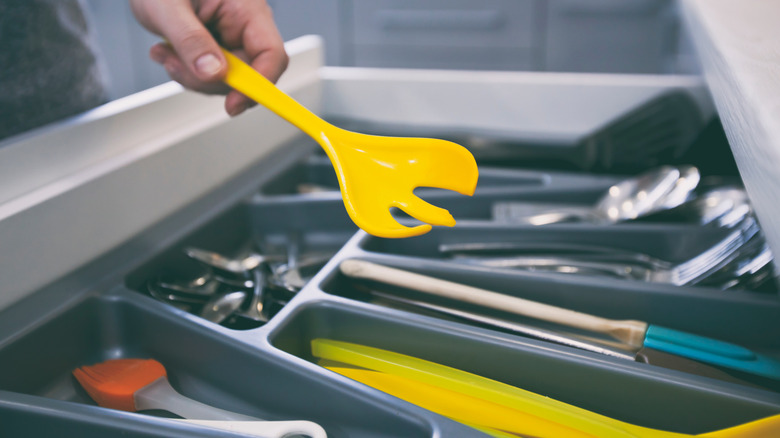 A hand taking a kitchen tool out of a drawer