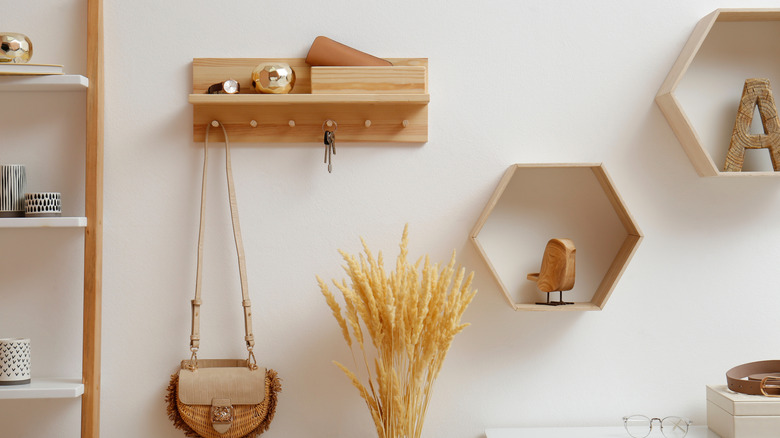 A hallway with decorative storage shelves, hooks, and cubicles