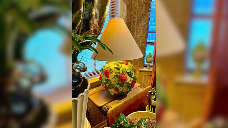 An Anthropologie strawberry lamp on a window table