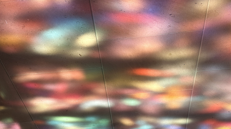 A tile floor is covered in colorful light reflections from a suncatcher