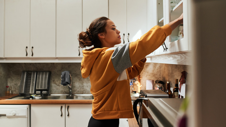 Woman reaching into kitchen cabinet