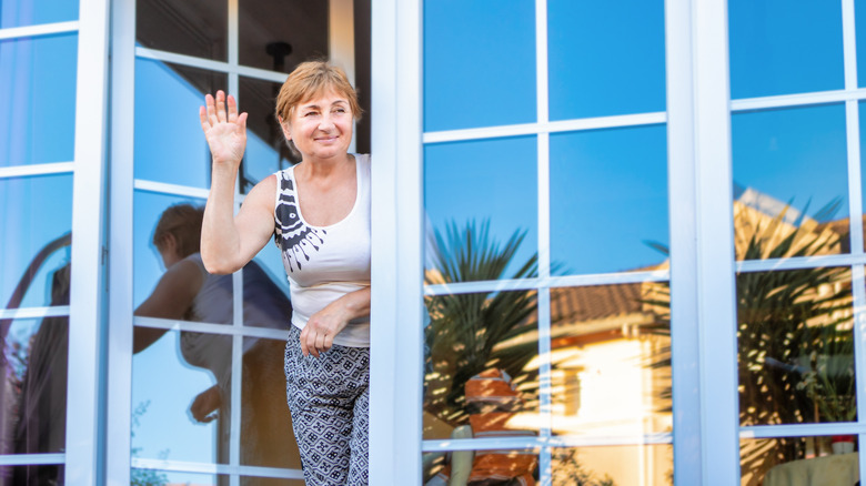 woman waves near mirrored windows
