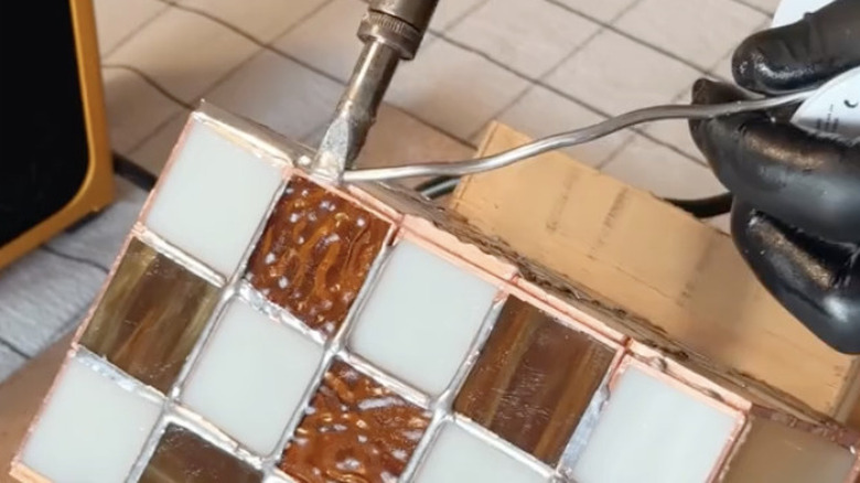 Carefully soldering the edges of the glass vase together