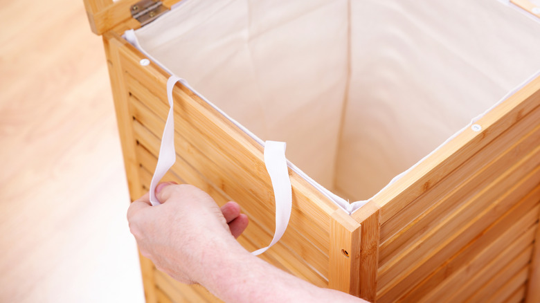 A person opens up a wood laundry hamper