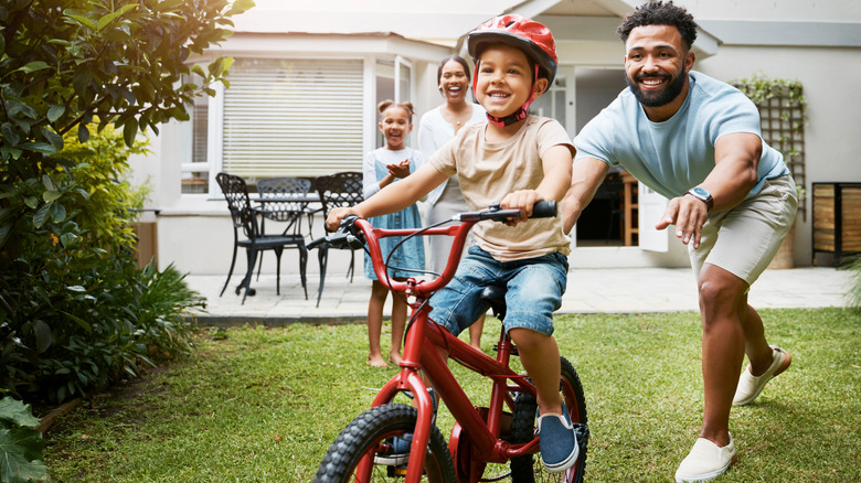 Father pushing son on bike 