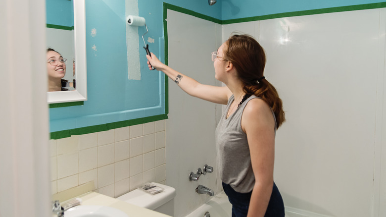 Woman painting bathroom wall