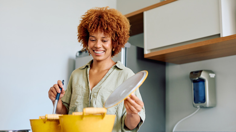 A woman in a kitchen preparing food on a stove