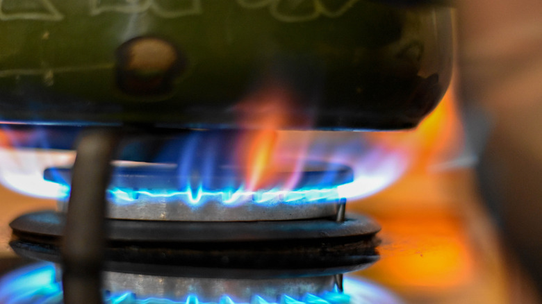 A gas flame beneath a frying pan on a stovetop