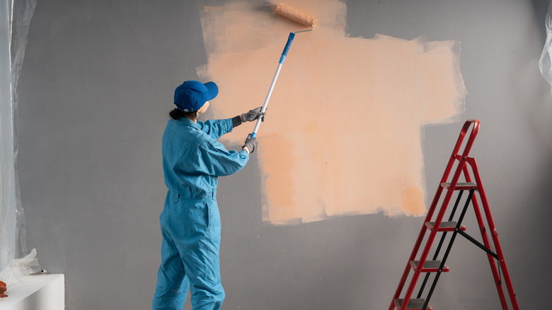 Woman paints new wall color over existing color.