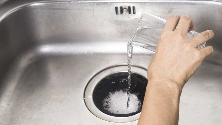 Pouring vinegar into garbage disposal with baking soda