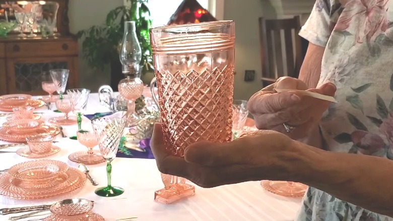 Person holding an Anchor Hocking's Miss America vintage glass tumbler with a table setting in the background.