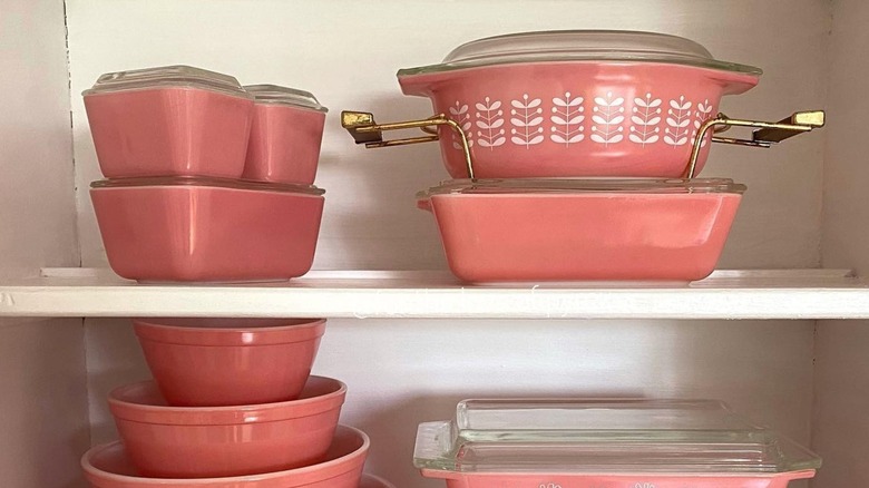 Pink stem casserole dish with other pink Pyrex containers in cabinet