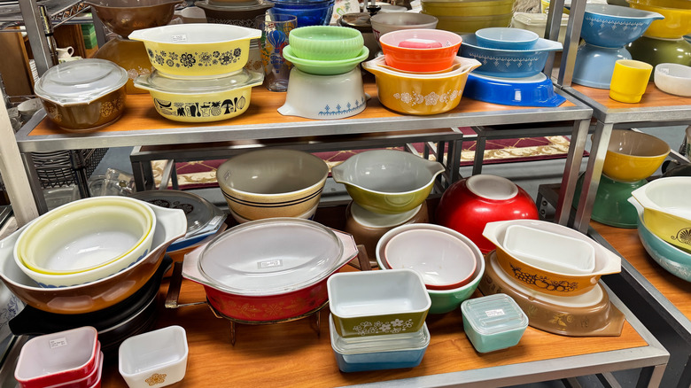 A bunch of vintage Pyrex dishes on a shelf at a thrift store