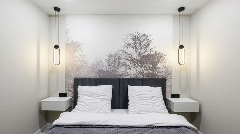A bedroom with a tree print wallpaper behind the bed