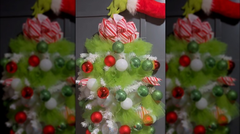 A decorative Grinch hand holds an upside-down Christmas tree
